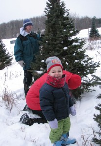 Josiah and Aunt Kat pose for a picture while Papa Dale cuts the tree